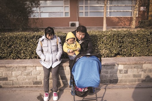 A couple and a child wait in the street of Beijing yesterday.
