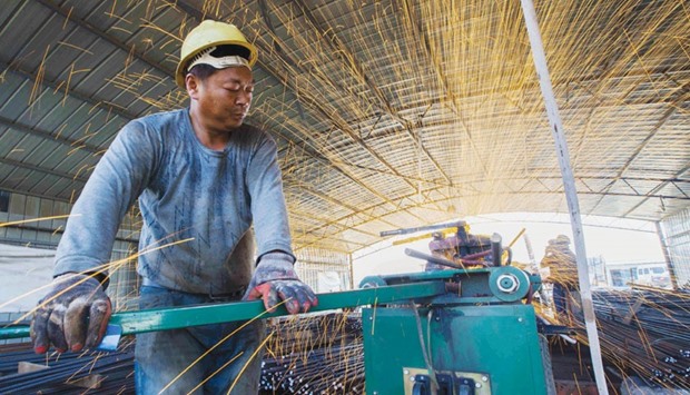 A labourer cuts steel bars at a railway bridge construction site in Lianyungang, China. Activity in Chinau2019s manufacturing sector contracted for a fifth straight month in December, an official survey showed yesterday, reinforcing fears the worldu2019s second-largest economy may be stuck in a protracted slowdown despite a flurry of stimulus measures.
