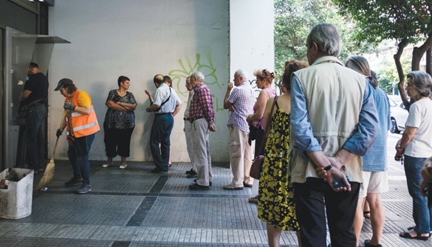 Customers form a queue outside an automated teller machine (ATM) operated by a National Bank of Greece branch in Thessaloniki, Greece. Data released by Greeceu2019s central bank this week showed that deposit outflows continued in November for a second consecutive month, even as the nationu2019s lenders plugged their capital shortfalls, and strict capital controls put in place last summer capped withdrawals and money transfers abroad.
