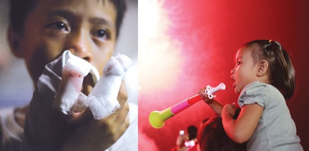 A boy injured from playing with fireworks shows off his bandages at the Jose Reyes Memorial Medical Centre in Manila, early yesterday. Right: A girl blows a party horn at midnight during New Year celebrations in Manila.