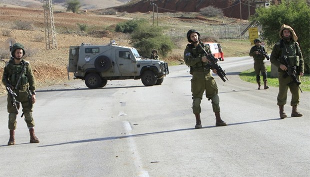 Israeli soldiers stand guard near the scene where two Palestinian men were shot dead by Israeli troo