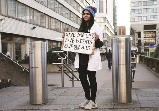 A doctor holds a placard during a strike outside St Thomasu2019 hospital in central London yesterday.