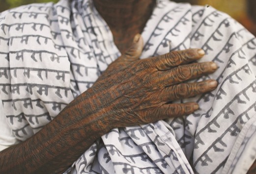 Punai Bai, 75, a follower of Ramnami Samaj, who has tattooed the name of Ram on her entire body, poses for a picture outside her house in the village of Gorba, in the eastern state of Chhattisgarh.