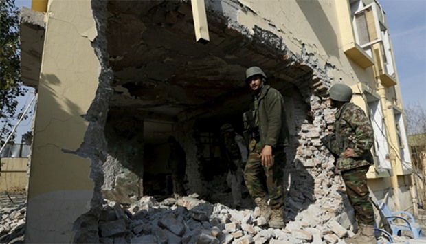 Afghan National Army (ANA) soldiers inspect a damaged building after a blast near the Pakistani cons