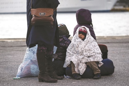 A migrant girl is wrapped up in a blanket after arriving yesterday at the port of Piraeus, near Athens, on board the passenger ferry Nissos Rodos along with other refugees and migrants.