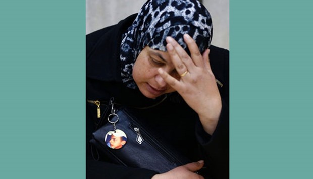 Suha, the mother of late Palestinian teenager Mohamed Abu Khdeir, waits in a courtroom at a Jerusalem district court yesterday before a sentencing hearing in the case of two young Jewish men convicted last year of the kidnap and murder of her son (seen on the badge).