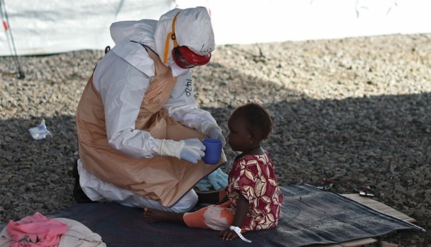 This file photo taken on November 15, 2014 shows an health worker wearing protective equipment giving to drink to an Ebola young patient at Kenama treatment center run by the Red cross Society. AFP