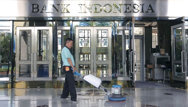 A worker cleans the entrance of the Bank Indonesiau2019s headquarters in Jakarta. The central bank cut its interest rates yesterday for the first time in nearly a year to try to lift an economy growing at its slowest pace since the global financial crisis.