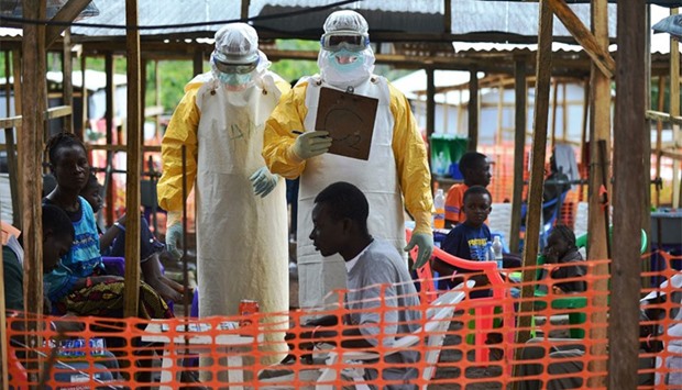 This file photo taken on August 15, 2014 shows an MSF medical worker, wearing protective clothing relays patient details and updates behind a barrier to a colleague at an MSF facility in Kailahun. AFP