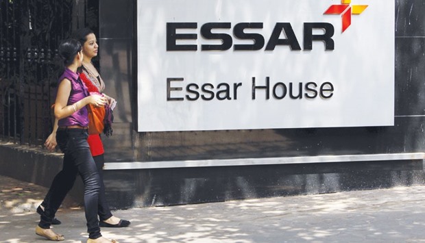 Employees walk past an Essar Group logo outside its headquarters in Mumbai. Indiau2019s largest-ever steel export deal, struck with Iran in 2014 to allow it to buy the metal without violating Western sanctions that are now set to end, has become mired in a dispute that has seen no payments made or shipments delivered since last fall.