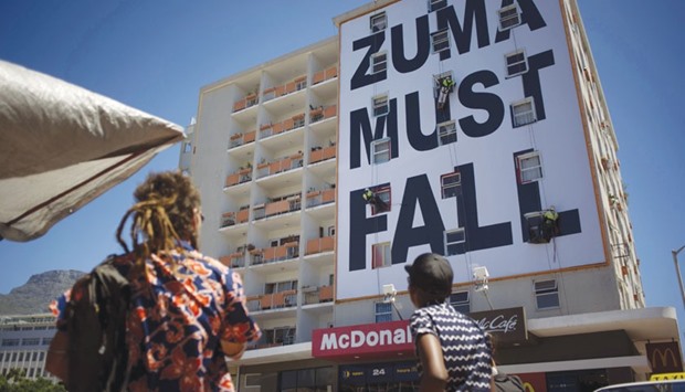 People watch as workers set up a giant banner referring the South African president in the trendy Long Street of central Cape Town.