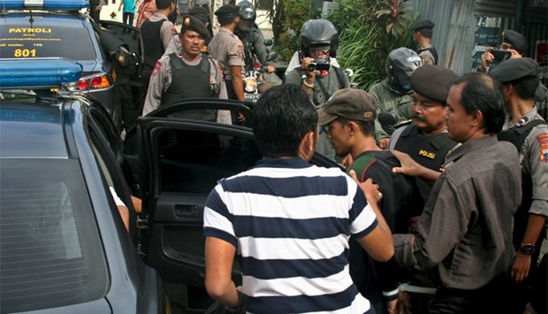 Police officers escort a man (C, with a cap) who was arrested during a raid in the Langgen village in Tegal, Indonesia Central Java, yesterday.  Reuters