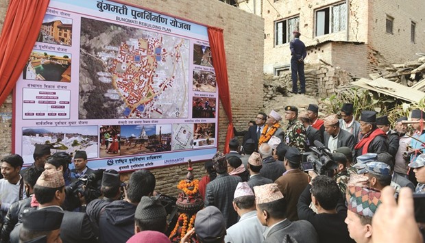 Nepalese Prime Minister KP Oli, centre left, unveils a poster as he formally begins the reconstruction campaign in Bungamati village on the outskirts of Kathmandu yesterday.