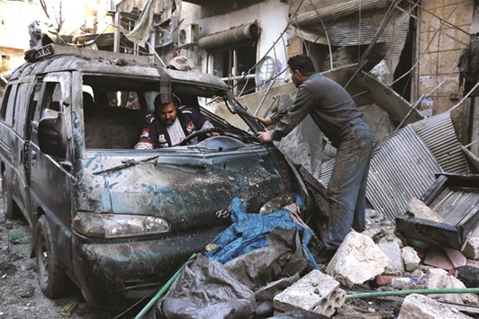 Syrian men inspect a damaged vehicle in the rubble following a reported air strike by Syrian government forces on the Sukkari neighbourhood of the northern city of Aleppo yesterday.