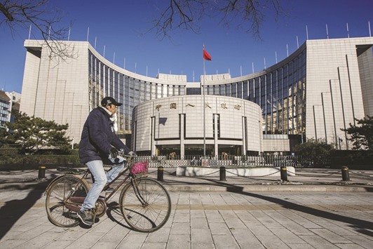 A man rides a bicycle past the Peopleu2019s Bank Of China headquarters in Beijing. Economists say the expansion of the Chinese economy was held back by sluggish domestic and external demand, weak investments, factory overcapacity and high property inventories, which exacerbated deflationary pressures in the economy.
