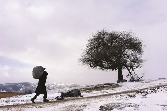 A migrant carries his bundle as he walks yesterday across a snow-covered field, after crossing the Macedonian border into Serbia near the village of Miratovac. More than 1mn migrants reached Europe in 2015, most of them refugees fleeing war and violence in Afghanistan, Iraq and Syria, according to the United Nations refugee agency.