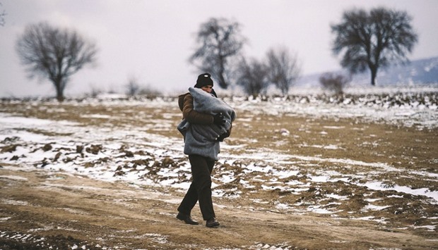 A migrant carries his child as he walks through a snowy field, after crossing the Macedonian border into Serbia near the village of Miratovac yesterday. More than 1mn migrants reached Europe in 2015, most of them refugees fleeing war and violence in Afghanistan, Iraq and Syria, according to the United Nations refugee agency.