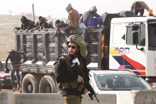 A member of the Israeli security forces stands guard as Palestinian workers are transported out of the Tekoa settlement south of Jerusalem yesterday, after Israeli authorities denied them entry following a stabbing attack.