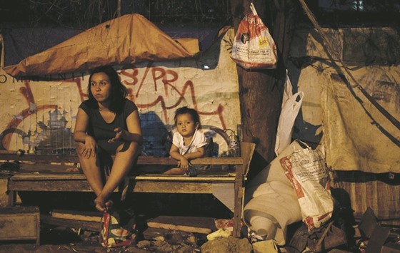 Mia Santos, 29, sits on a wooden bed with her baby girl Eunice, two, at a shack along a street in Manila. Her husband Elmer earns two dollars a day by picking recyclable materials among garbage that he can sell to junkshops.