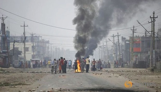 Protesters stand near burning tyres as they gather to block the highway connecting Nepal and India, during a general strike called by Madhesi protesters demonstrating against the new constitution in Birgunj, near Kathmandu.
