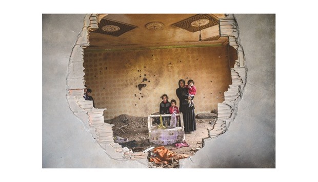 A woman and her children stand in the ruins of battle-damaged house in the Kurdish town of Silopi, in southeastern Turkey, near the border with Iraq.