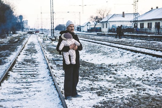 A man holding his baby while waiting with other migrants and refugees at a train station  in southern Serbian town of Presevo yesterday. The UNHCR has been doing an important job in protecting refugees, but it cannot possibly address their needs alone. Its budget of $7bn in 2015 may seem large, but it amounts to only about $100 per displaced person u2013 not enough to cover even essentials like food and shelter.