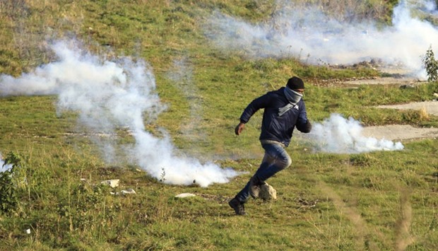 A migrant runs yesterday near clouds of tear gas in a field near Calais, France, as migrants gather in the hopes of attempting to board lorries and making their way across the Channel to Britain.