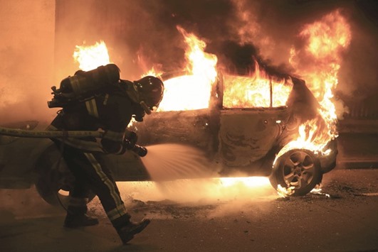 A firefighter extinguishes a burning car following New Year celebrations in Lille, northern France.