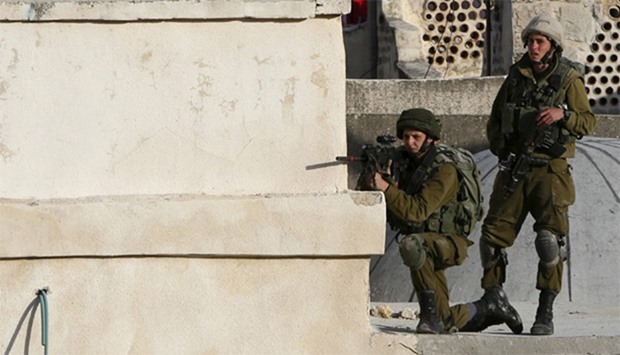An Israeli soldier aims his weapon