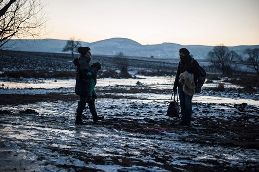A woman carrying her baby walking on a patch of ice on a frozen field after crossing the Macedonian border with other migrants and refugees into Serbia, near the village of Miratovac, yesterday.