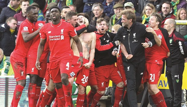 With his shirt off, Liverpoolu2019s midfielder Adam Lallana (centre) celebrates scoring the late winning goal with teammates and manager Jurgen Klopp (third right), as Norwich Cityu2019s coach Alex Neil (right) looks on during the English Premier League match at Carrow Road in Norwich, eastern England. (AFP)