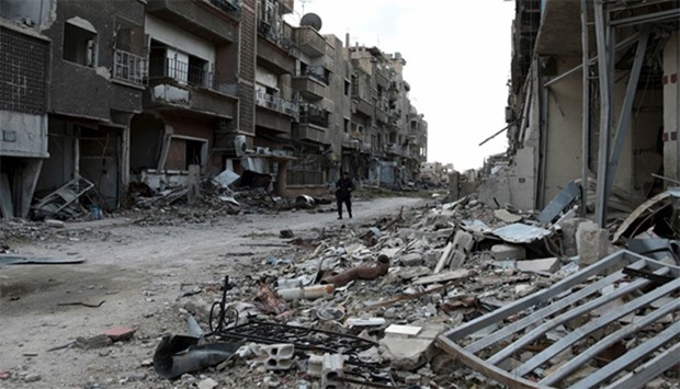 A Syrian Army fighter walks past damaged buildings in Jobar