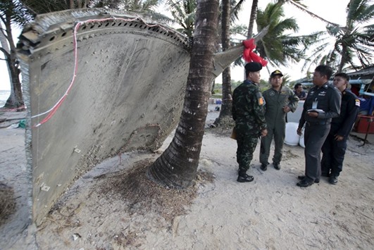 Thai army members stand next to a piece of suspected plane wreckage which has been found off the coast of southern Thailand in Nakhon Si Thammarat province yesterday.