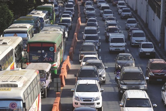 A major thoroughfare is clogged with traffic in Manila. Right: Maria Zurbano (right) travels in a van to work in suburban Manila.
