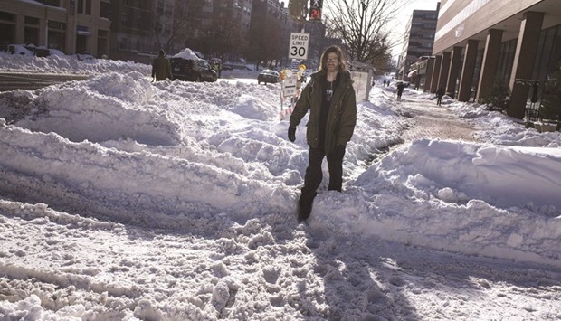A man walks over a pile of snow to cross a street yesterday in Washington, DC