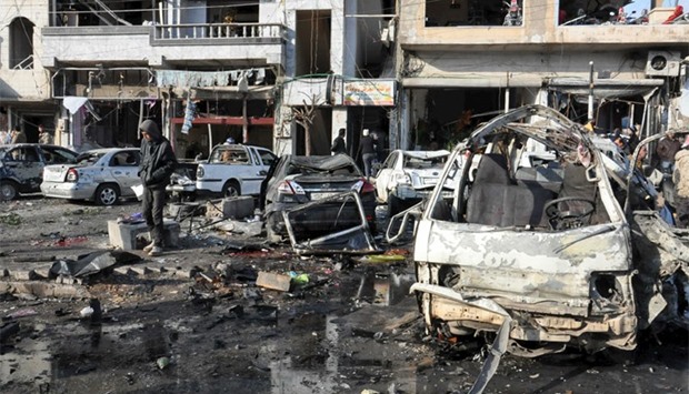 People inspect the site of a double bomb attack in the government-controlled city of Homs, Syria.