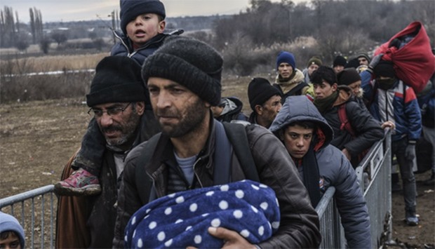 Migrants and refugees wait in line for security check