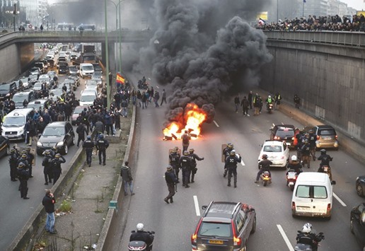 French policemen look on as taxi drivers set tyres on fire during a demonstration in Paris yesterday.