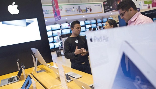An Apple salesperson speaks to customers at an electronics store in Mumbai. As red-hot sales in China show signs of cooling, the company executives are touting Indiau2019s growing appetite for iPhones.