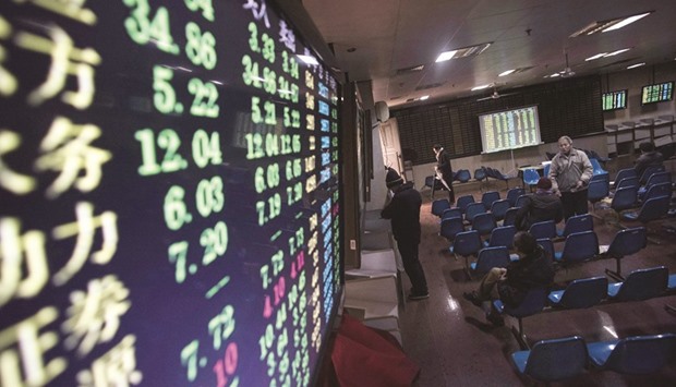 Investors looking on beside an electronic board showing stock information at a brokerage house in Shanghai. Shanghai stocks closed lower yesterday, extending a 6.42% plunge the previous day on worries over the weak economy after data showed industrial profit accelerated declines in December