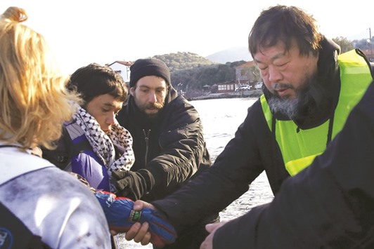 Chinese artist Ai Weiwei helps an Afghan migrant as he arrives with other refugees and migrants on a raft on the Greek island of Lesbos, in this January 25 file picture.