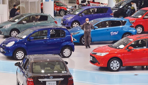 Customers check vehicles from Toyota at the companyu2019s showroom in Tokyo. The Japanese firm is likely to keep the top automaker crown for at least another year, but a slowdown in top vehicle market China could hurt its numbers, analysts said yesterday.
