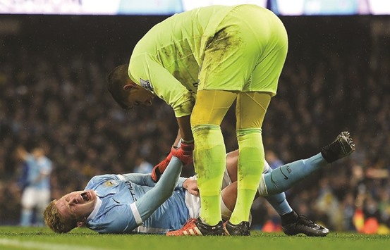 Manchester City midfielder Kevin De Bruyne writhes in pain as Evertonu2019s Spanish goalkeeper Joel Robles talk to him before being stretchered off during the English League Cup second leg semi-final match at the Etihad Stadium in Manchester, north west England, on Wednesday. (AFP)