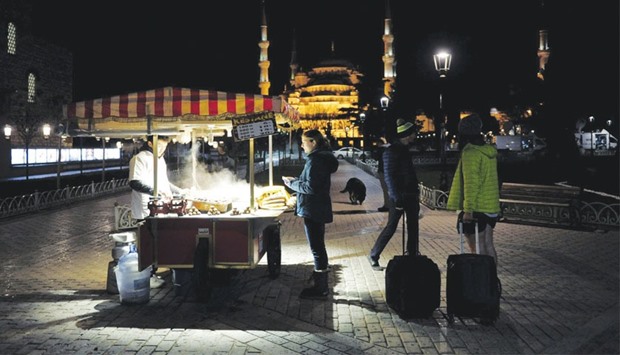 Foreign tourists stand next to a street vendor at Sultanahmet square in Istanbul on January 12. Tourism accounts for 4.5% of Turkish output.