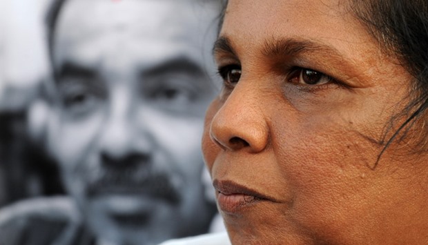 Sandhya Eknaligoda stands before an image of her husband, missing cartoonist and journalist Prageeth Eknaligoda.