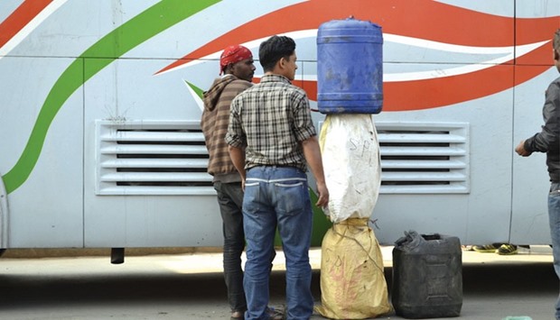 Men in Kathmandu unload fuel smuggled over the border from India on a bus.