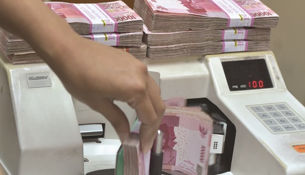 An employee counts Indonesian rupiah banknotes at a money changeru2019s office in Jakarta. The rupiah, Argentinau2019s peso and the Brazilian real are seen falling the most in the next 12 months, according to data compiled by Bloomberg.