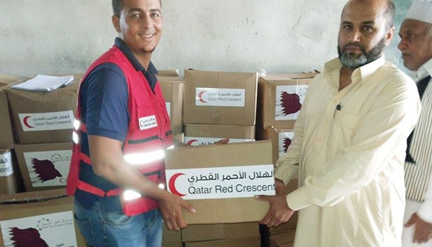 A man receives a food carton from a QRCS volunteer.