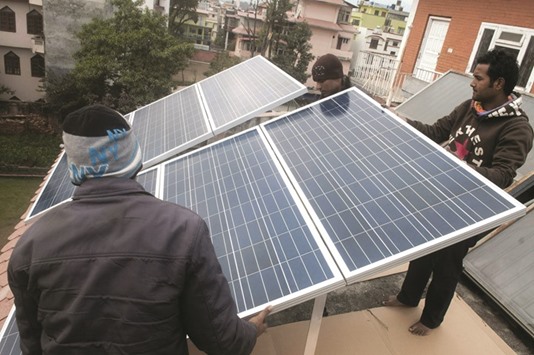 Technicians fixing a solar panel on the roof of a private house in Kathmandu.