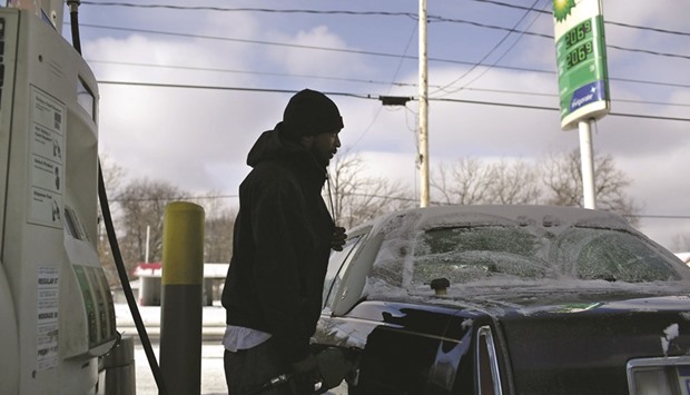 A motorist is silhouetted as he pumps fuel into his vehicle at a BP station in Flint, Michigan, US (file). Oil futures dropped 30% in 2015, and averaged the lowest level since 2004. US supplies rose 102mn barrels over the year, the biggest jump since at least 1920 in  government data. The 62% loss since 2013 exceeded the slump driven by the Asian economic crisis from 1997 to 1998.